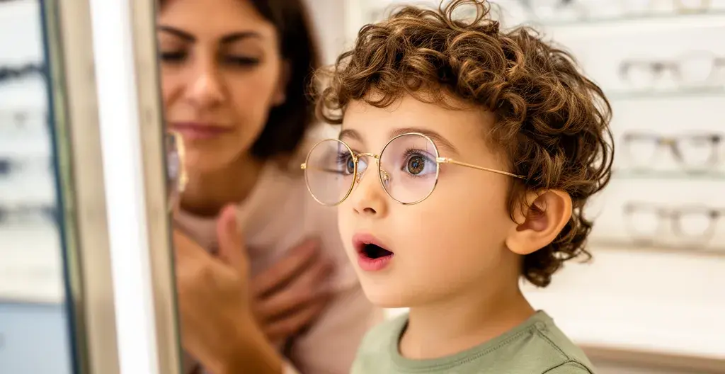 Enfant essayant des lunettes chez l'opticien avec parent en arrière-plan